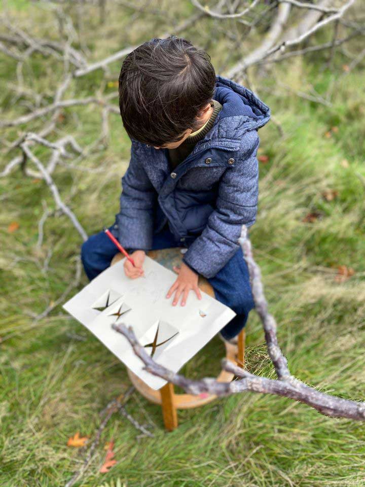 kind zit op gras en tekent